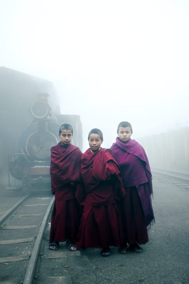 Novice monks posing in front of a vintage steam engine in Darjeeling, West Bengal.