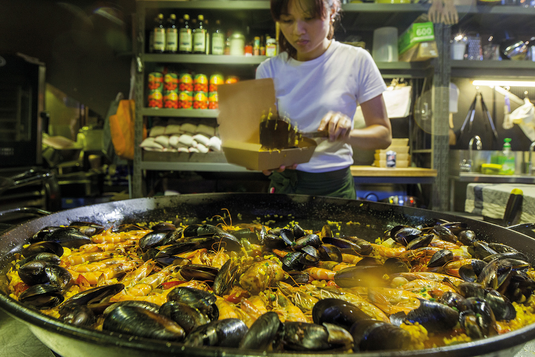 A server scoops up fresh seafood paella.